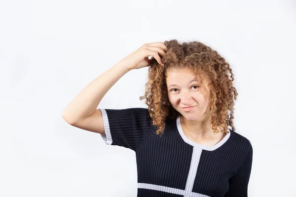 Confused young girl scratching her head looking frustrated over white background. Human facial expression, sign symbol body language.