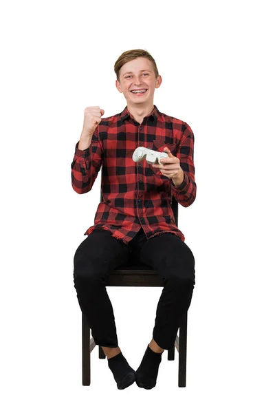 Cheerful teenage boy seated on chair playing video games isolate — Stock Photo, Image