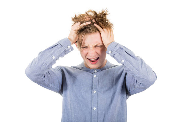 Frustrated teenage boy messing up and pulling his hair, hands to