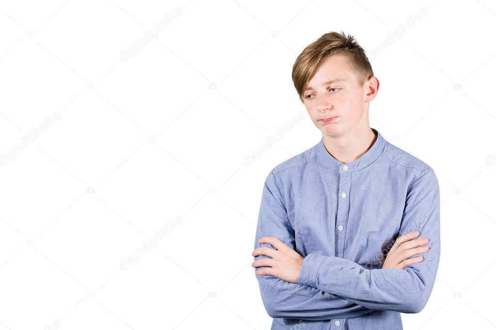 Disappointed teen boy keeps arms crossed looking displeased asid