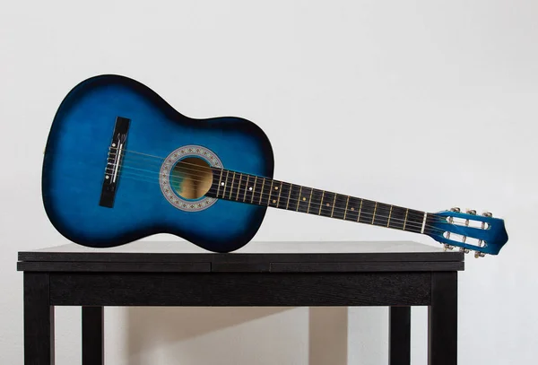 Guitarra acústica azul em uma mesa de madeira preta isolada em wa cinza — Fotografia de Stock