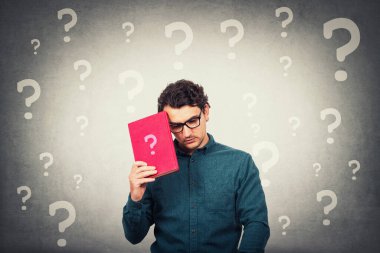 Kafası karışmış öğrenci üzgün görünüyor. Elinde soru işareti ve kafasının etrafında farklı sorgulama sembolleri olan bir kitap tutuyor. Zor eğitim süreci kavramı. Kötümser adamın öğrenme sorunları vardır.