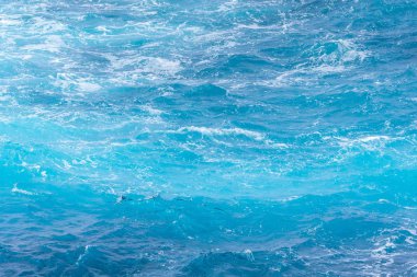 Güneşli bir günde mavi suyla Atlantik Okyanusu. Dalgalar, köpük ve deniz yolculuğunun yol açtığı uyanma.