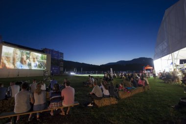 Ceahlau, Romanya - 13 Ağustos 2019: Su Müziği Festivali, Ceahlau, Romanya yerel etkinlik. Film projeksiyon ekranında insanların gece sahnesi açık havada