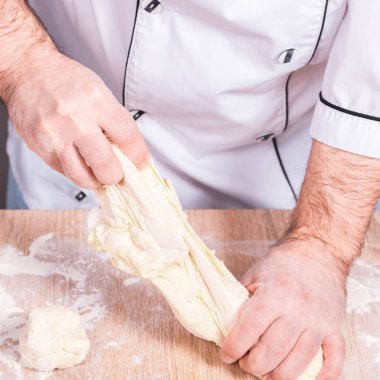 Erkek aşçı hamur yoğurur, elleri yakın.
