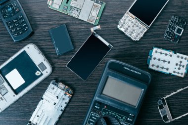 Ahşap arkaplanda parçalanmış cep telefonu ve araçları