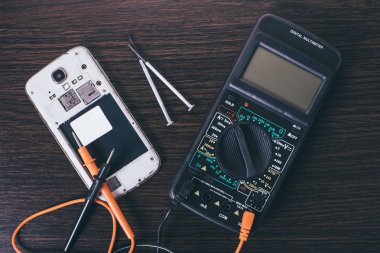 Ahşap arkaplanda parçalanmış cep telefonu ve araçları