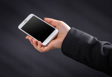 Siyah arka planda kadın eli cep telefonu.