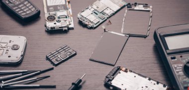 Ahşap arkaplanda parçalanmış cep telefonu ve araçları