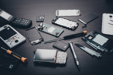 Ahşap arkaplanda parçalanmış cep telefonu ve araçları