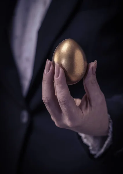 golden chicken egg in female hand closeup