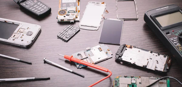 disassembled mobile phone and tools on wooden background