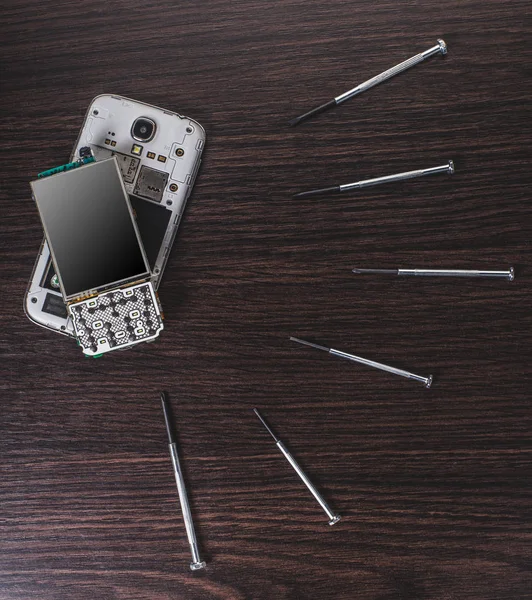 disassembled mobile phone and tools on wooden background