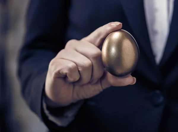 golden chicken egg in female hand closeup