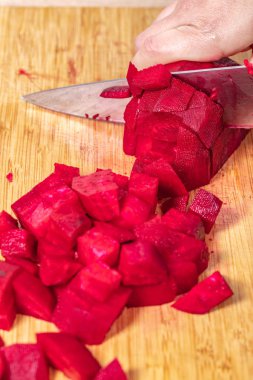 Aşçı, ahşap bir tahtanın üzerinde kırmızı pancar keser, yemek pişirmeye hazırlanır.