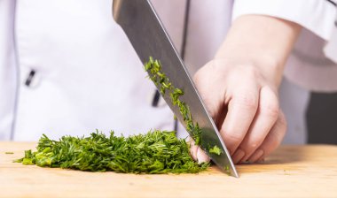 Ahşap bir tahtanın üzerinde doğranmış yeşil dereotu pişirin.