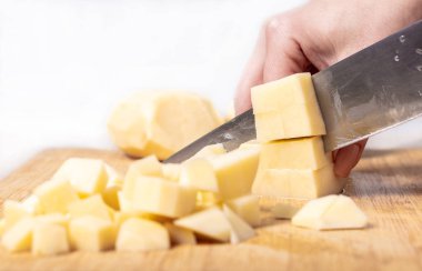 Aşçı patatesleri ahşap bir tahtada keser, yemek hazırlar.