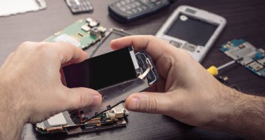 Cep telefonu tamiri, ahşap masaya yakın duran eller.