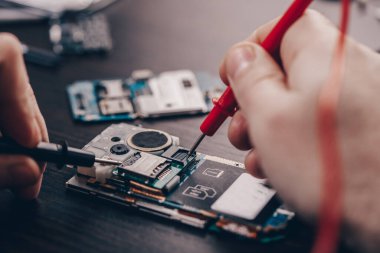 Cep telefonu tamiri, ahşap masaya yakın duran eller.
