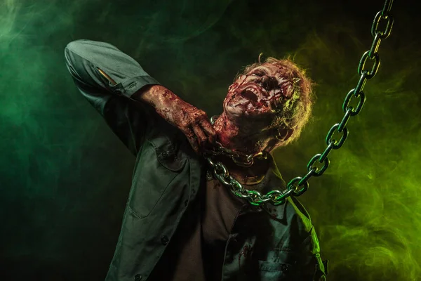 Horror zombie. Halloween party. Close-up portrait of a horrible scary zombie man in smoke. Chains. — Stock Photo, Image