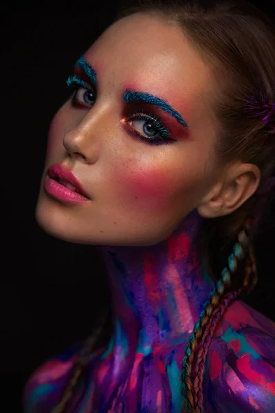 Portret van mooie jonge vrouw met heldere roze en blauwe kleuren, kunst make-up mode, gezicht kunst op donkere achtergrond — Stockfoto