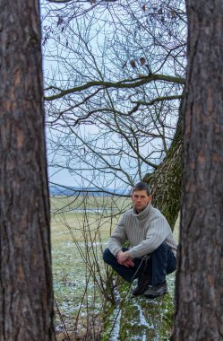 Genç adam kazak ağacında oturmak