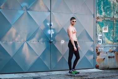 Kapının önünde yakışıklı genç adam Runner ayakta, güneş gözlüğü ile yarı çıplak vücut. Fitness, egzersiz, spor, yaşam tarzı konsepti.