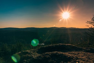 Ağaçlar ve karanlık gökyüzü ile kaya üzerinde Güzel gün batımı