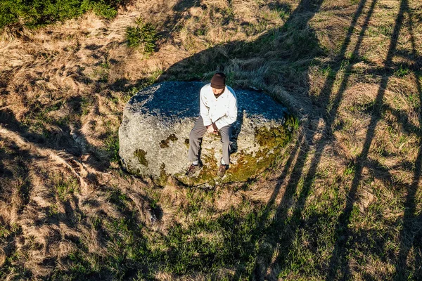 Young man hiker in black cap sit on stone from up, Novohradske h — Stock Photo, Image