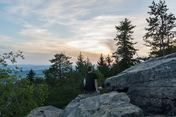 Young man sitting on stone rock in czech landscape with trees at — 스톡 사진