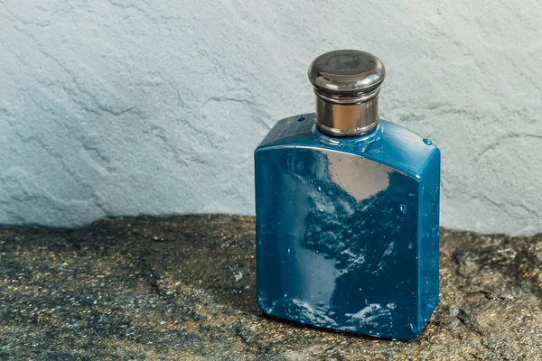 Frasco aftershave azul na textura de pedra molhada — Fotografia de Stock