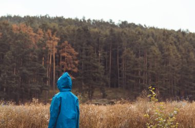 Küçük çocuk arazi ve orman ile mavi yağmurluk standı. Açık 