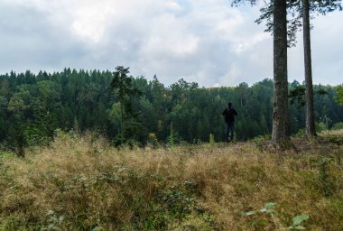 Düşünceli genç adam dramatik gökyüzü ile Çekoslovakya ormanında duruyor