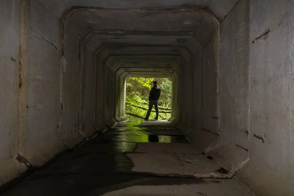 Joven parado en el extremo del túnel de hormigón en jac negro — Foto de Stock