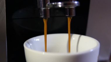 Kahve makinesinde kahve fincanı kabarık mutfak arka planında.