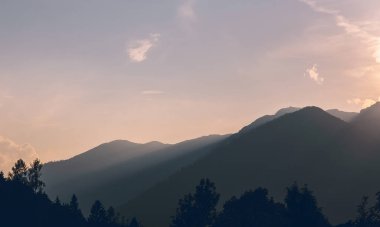 Ağaçlı ve gün batımlı Alpler Dağı silueti. Avusturya manzarası