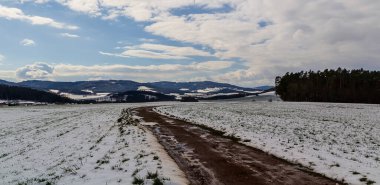 Kış mevsiminde tepeler ve ağaçlar Toprak yolu ve kar tarlası olan Çek manzarası
