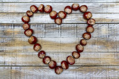 Tahta masanın üzerinde kestane ve palamut kalp şeklinde düz yatıyordu. Sonbahar, düğün manzaralı arka plan