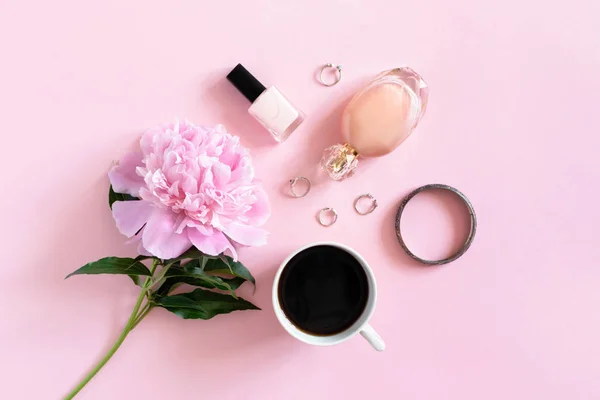 Coffee, peony, cosmetics and accessory on a pink pastel background