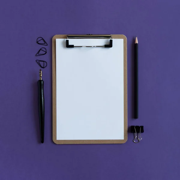 Clipboard with white blank paper, black paper clips, calligraphic pen, pencil on a ultra violet background