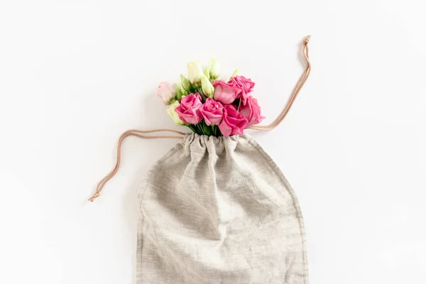 Bouquet of eustoma flowers in canvas bag on white background