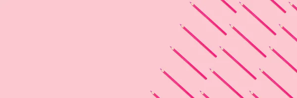 Banner with pink pencils pattern on a pastel background. Monochromatic creative concept with copy space.