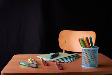 Siyah arka plan üzerine okulda masa mavi metal sepetteki renkli kalemler