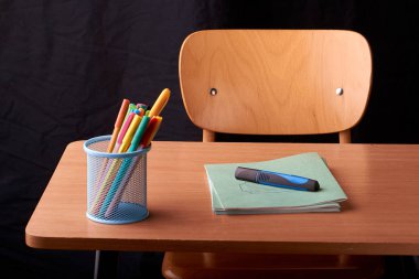 Siyah arka plan üzerine okulda masa mavi metal sepetteki renkli kalemler