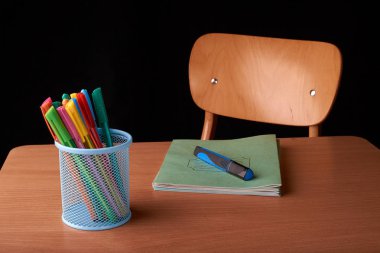 Siyah arka plan üzerine okulda masa mavi metal sepetteki renkli kalemler