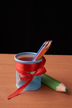 teneke kutu siyah ahşap masa üzerinde renkli kalemler