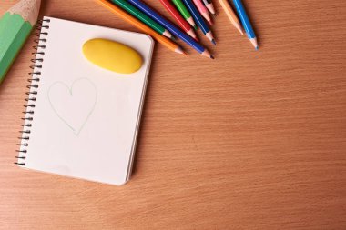 masanın üzerine siyah arka plan üzerinde renkli kalemler ile boş defter sayfası