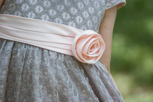 A close up of a dress of little girl with a large flower outside