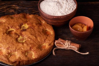 kayısı pasta ve bir kase un ve diğer malzemeler ahşap tablo