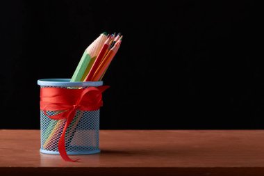 Metal tutucu siyah arka plan üzerine ahşap masa üzerinde birçok kalemler